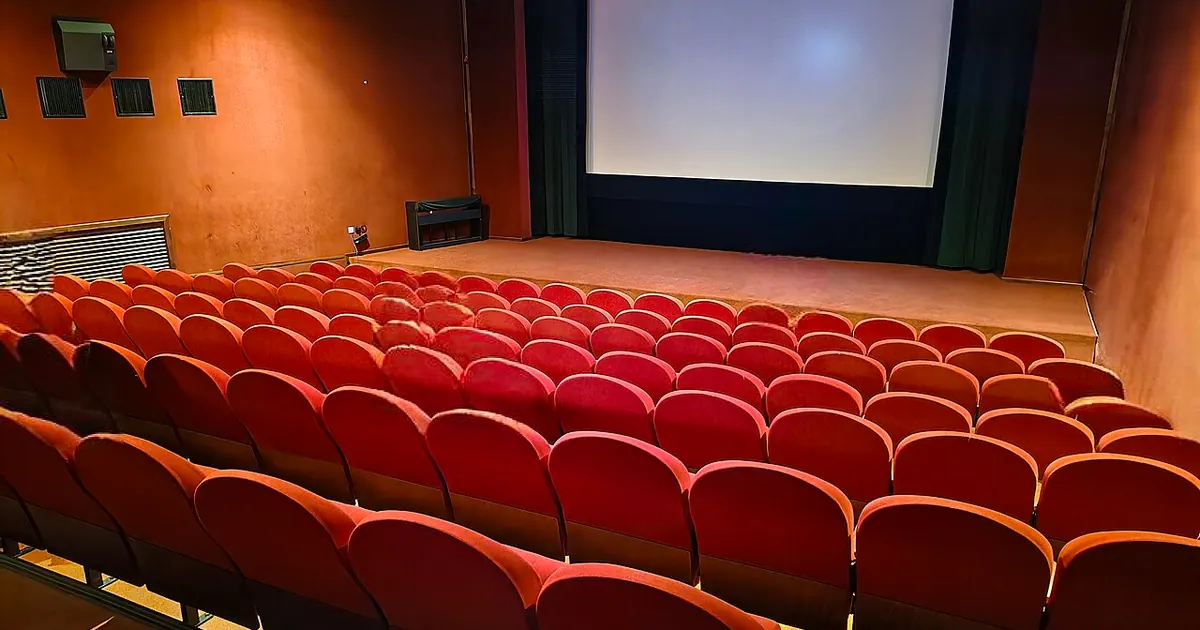 Empty cinema auditorium with red seats facing the screen