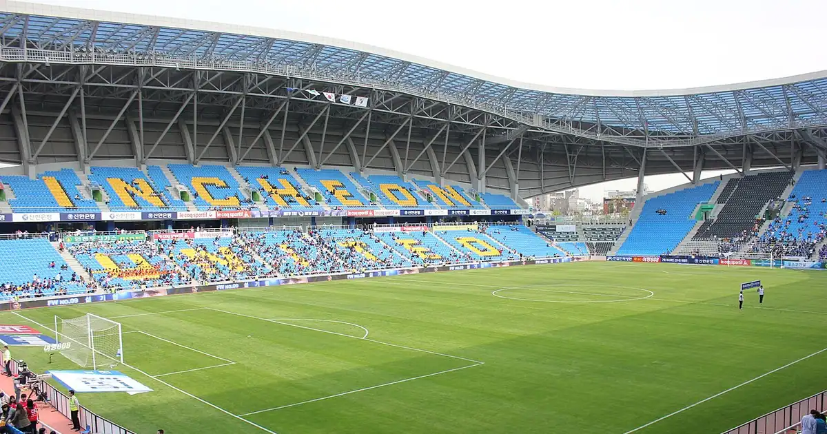 Football stadium with a green pitch and empty blue seats