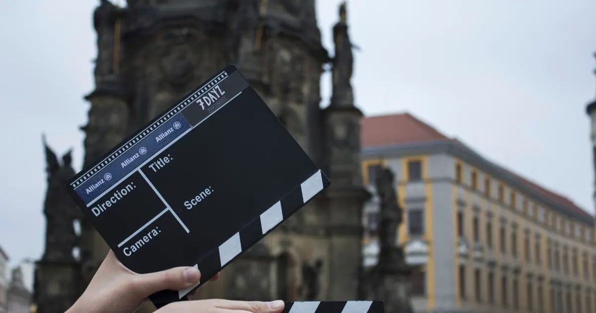Film clapperboard held up in front of old city buildings