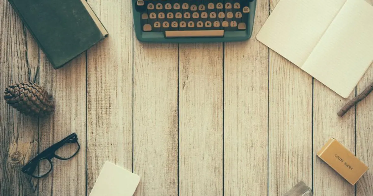 Typewriter, glasses and notebook on a wooden desk