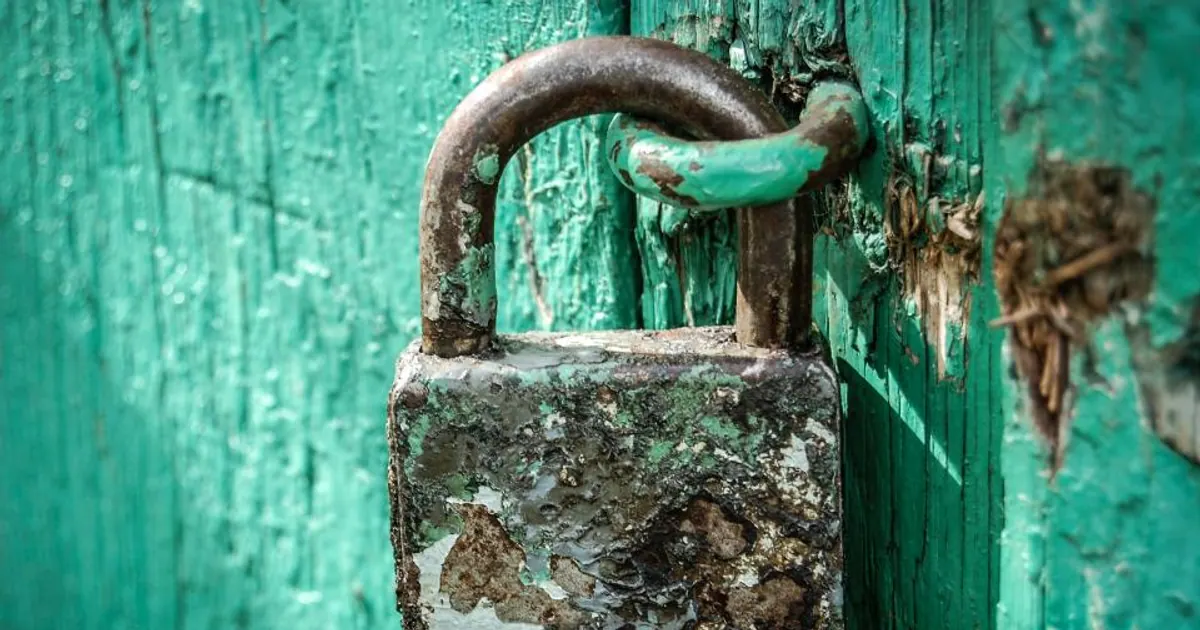 Old padlock on a weathered green door