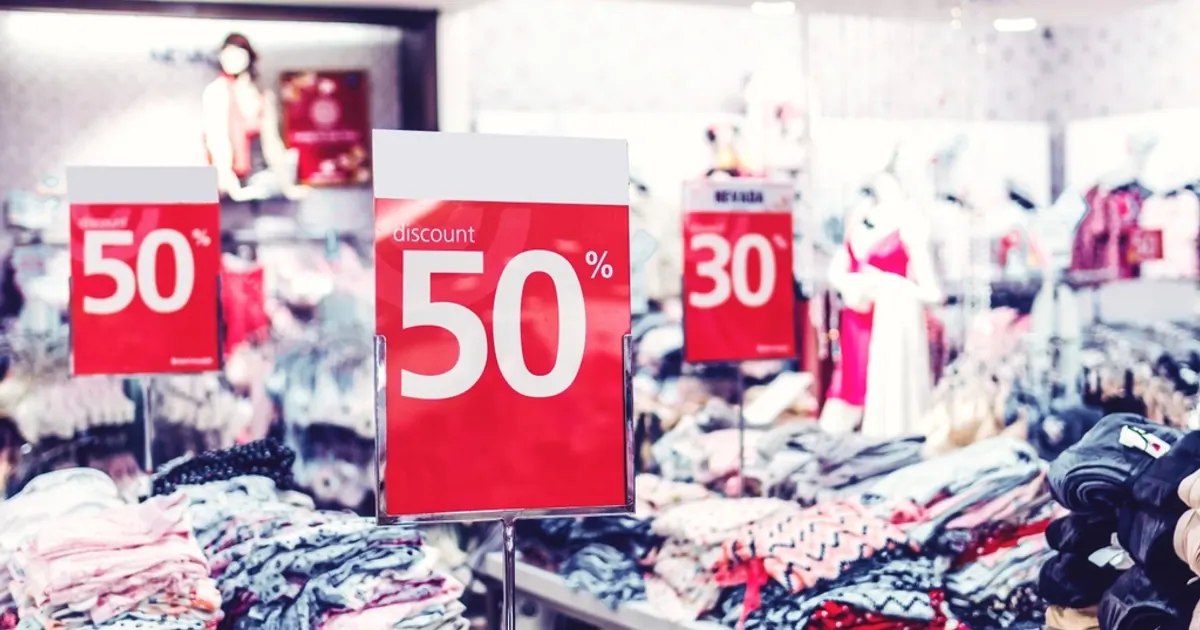 Red 50 percent off sale signs above clothes in a shop