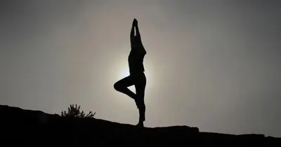 Silhouette of a person doing a yoga pose at sunset