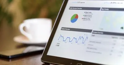 Tablet showing charts next to a cup of coffee on a desk